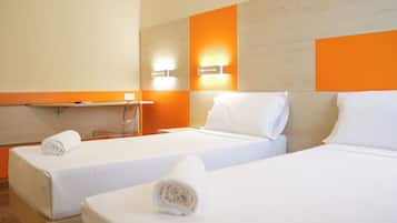 A hotel room with two beds, a small desk, and a chair.