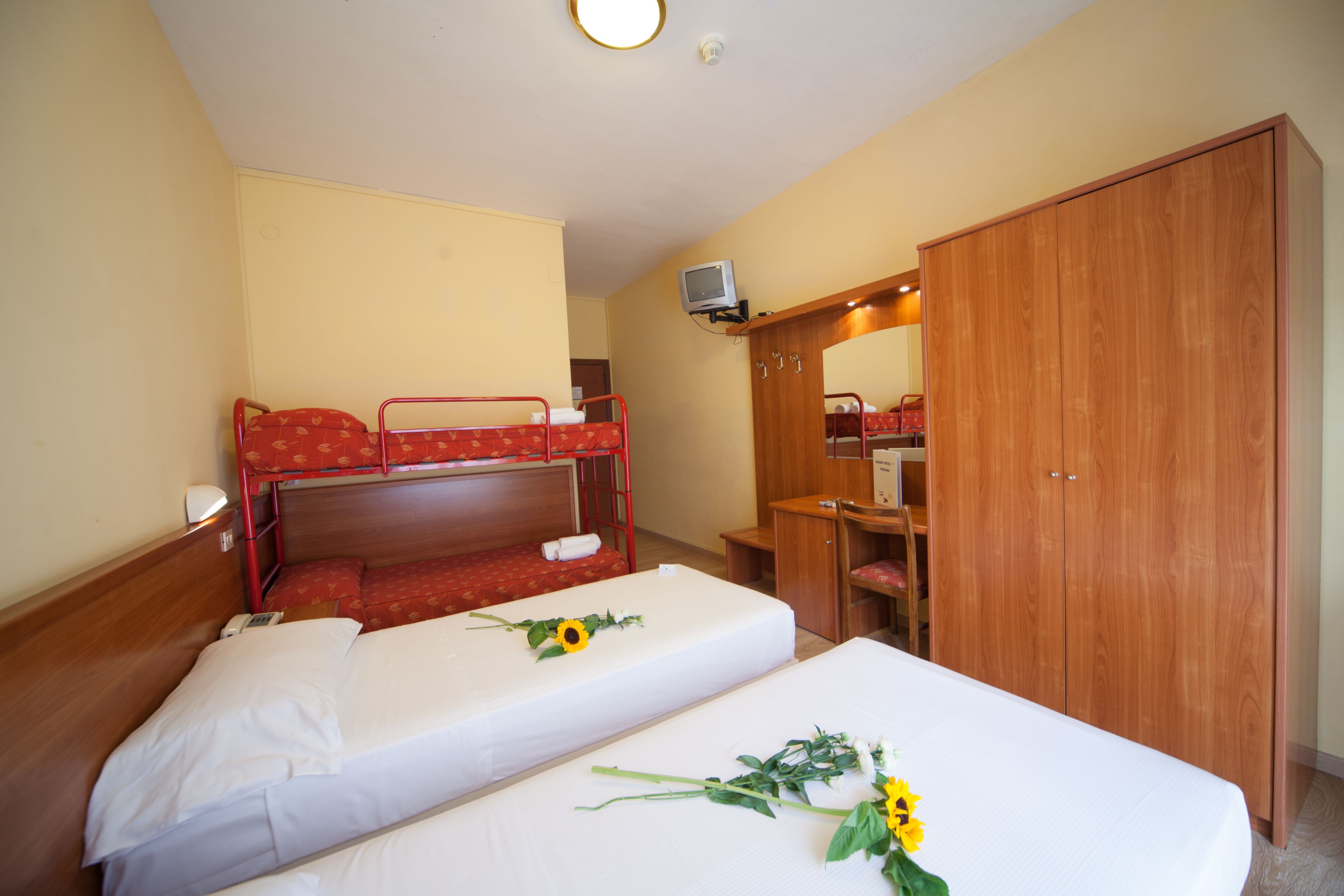 Een hotelkamer met twee enkele bedden, een houten garderobe, een bureau en een televisie.
