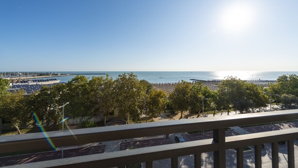 A coastal view with a clear sky, a beach, and a parking area with cars. - Hotel Regent (Pescara)