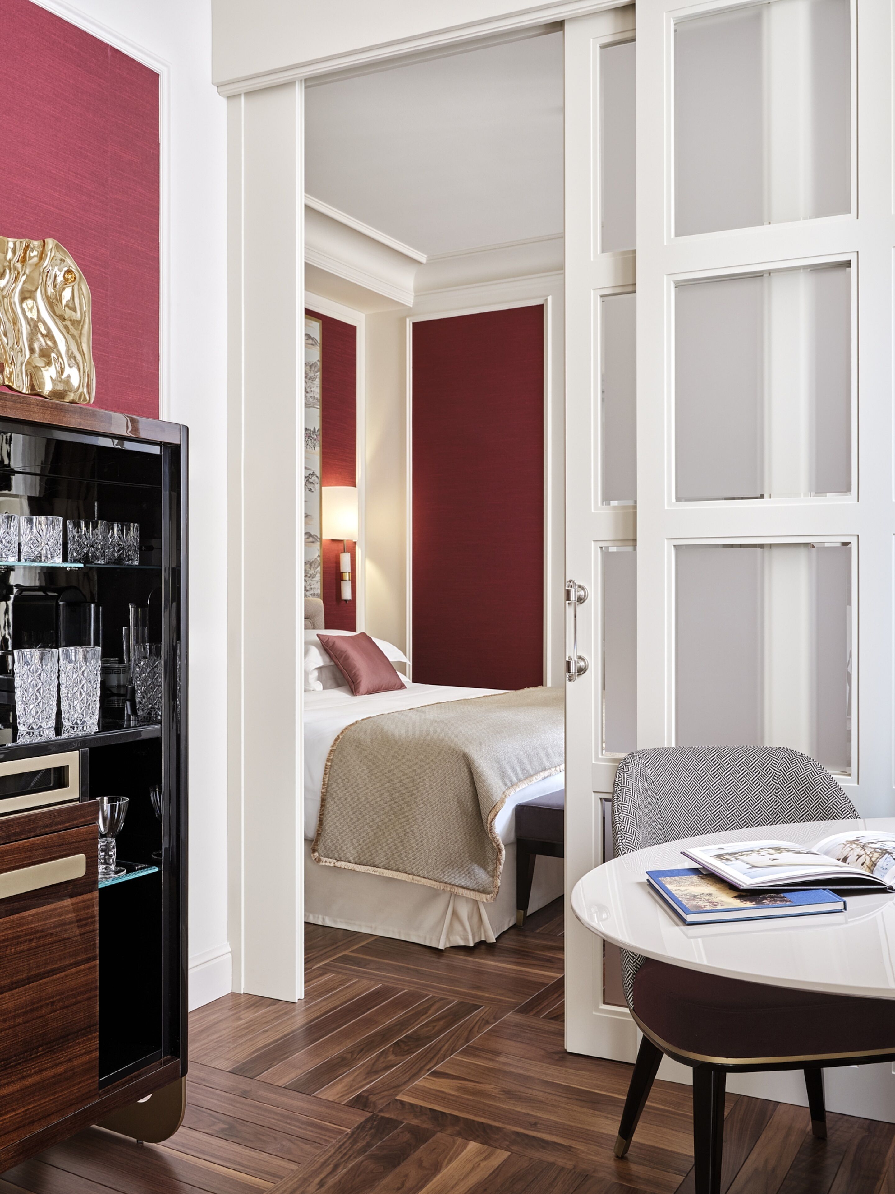 A hotel room with a bed, a bedside table with a book, a chair, and a wardrobe.