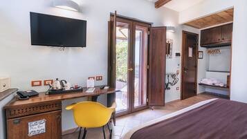 Een hotelkamer met een bed, een bureau met stoel, een televisie en een schuifdeur naar buiten.