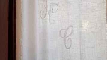 A white curtain with embroidered initials.