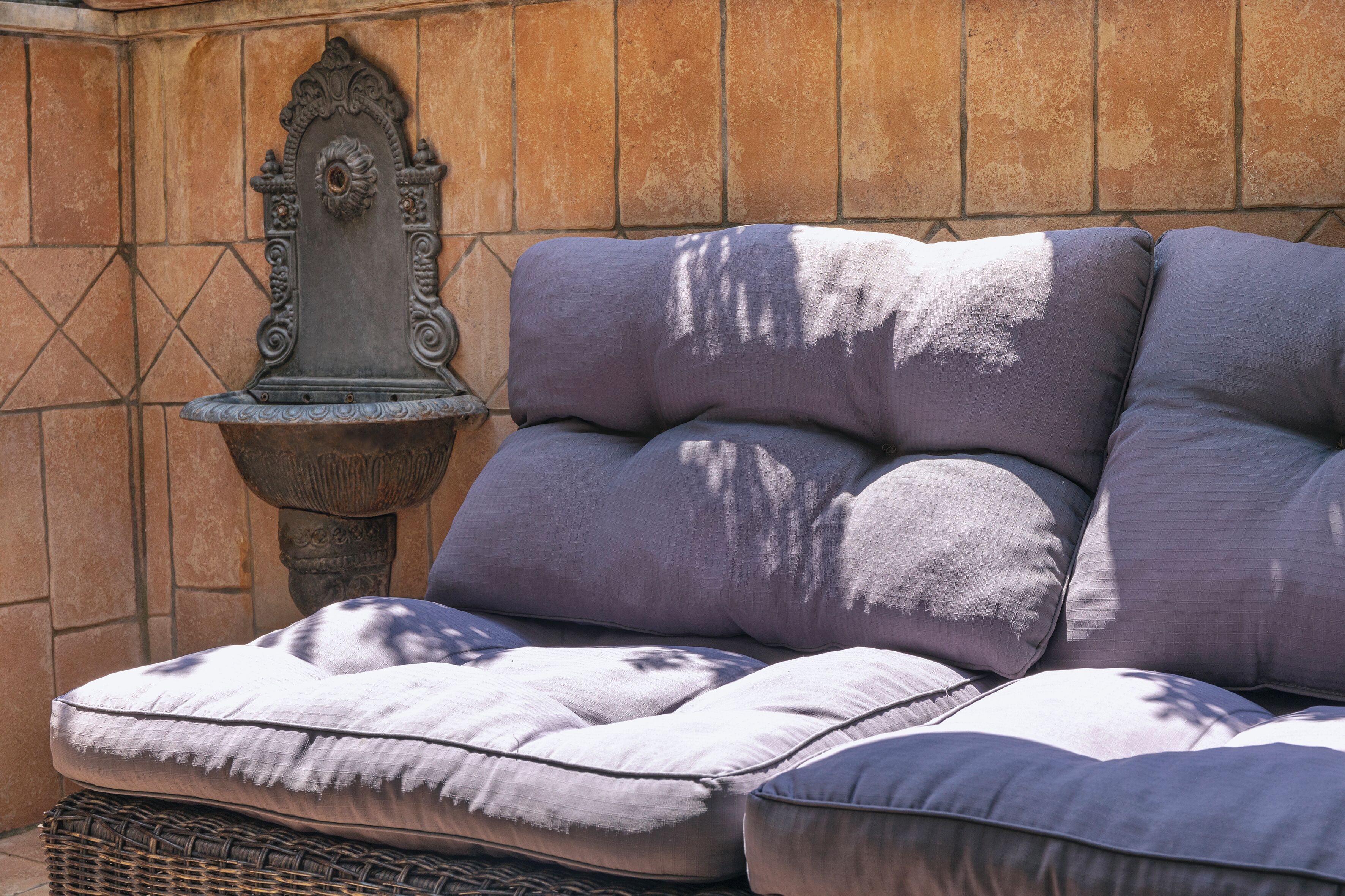 A sectional sofa with multiple cushions against a tiled wall.