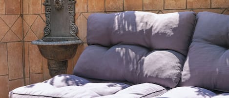 A sectional sofa with multiple cushions against a tiled wall.
