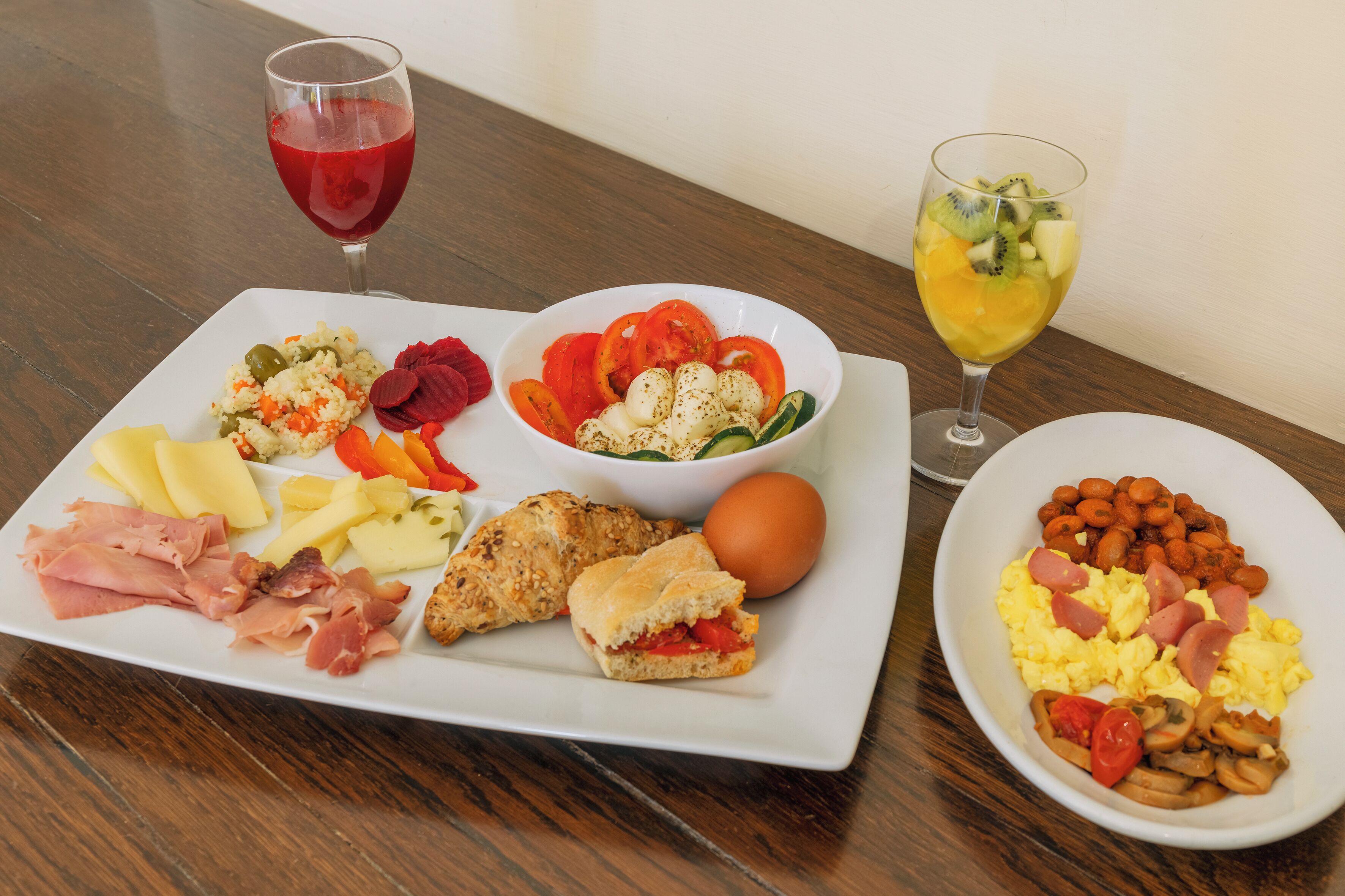 A breakfast tray with various foods and drinks on a wooden table.