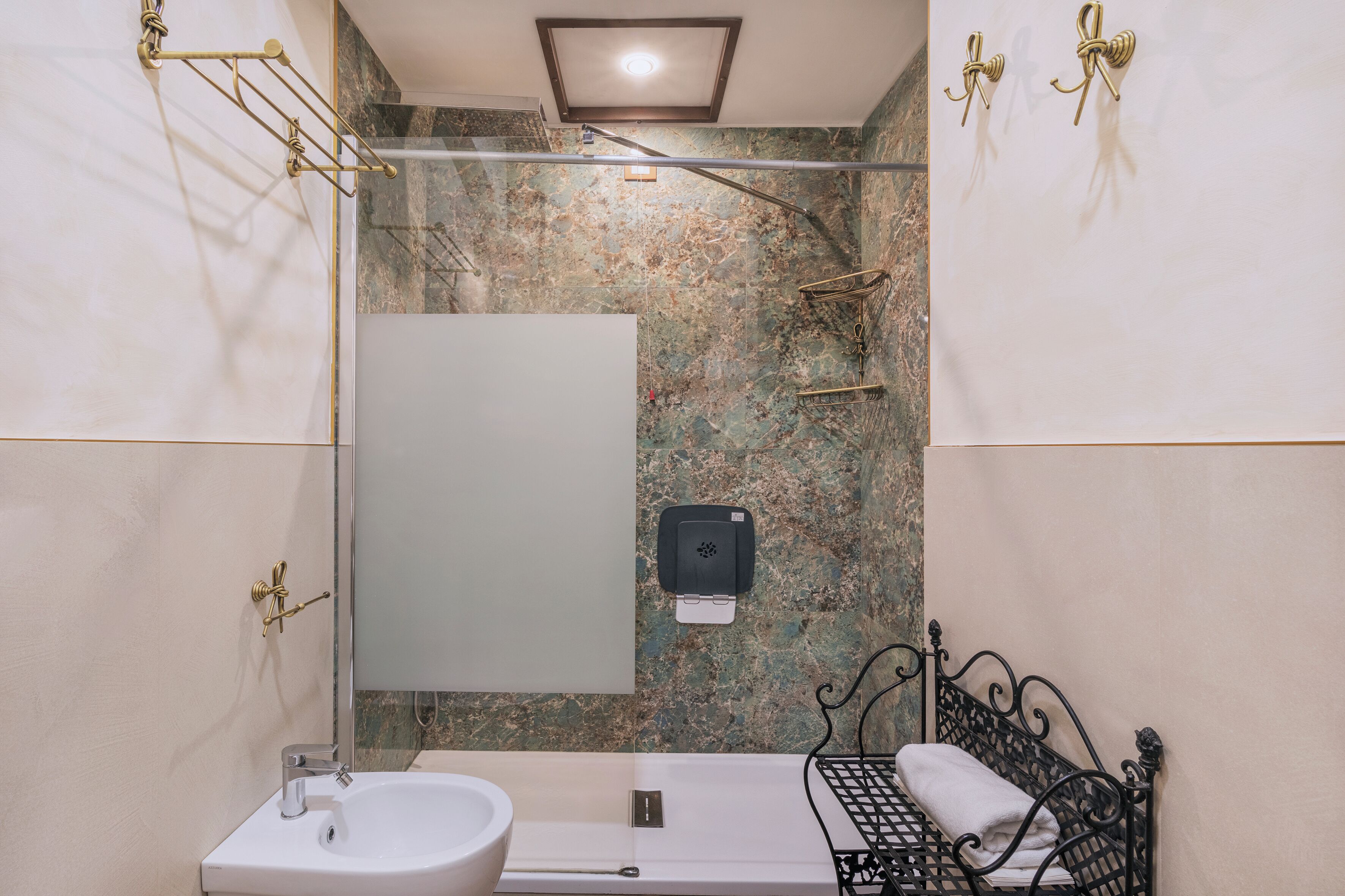 Ein Badezimmer mit Waschbecken, Spiegel, Handtuchhalter, Dusche und einem Bett.