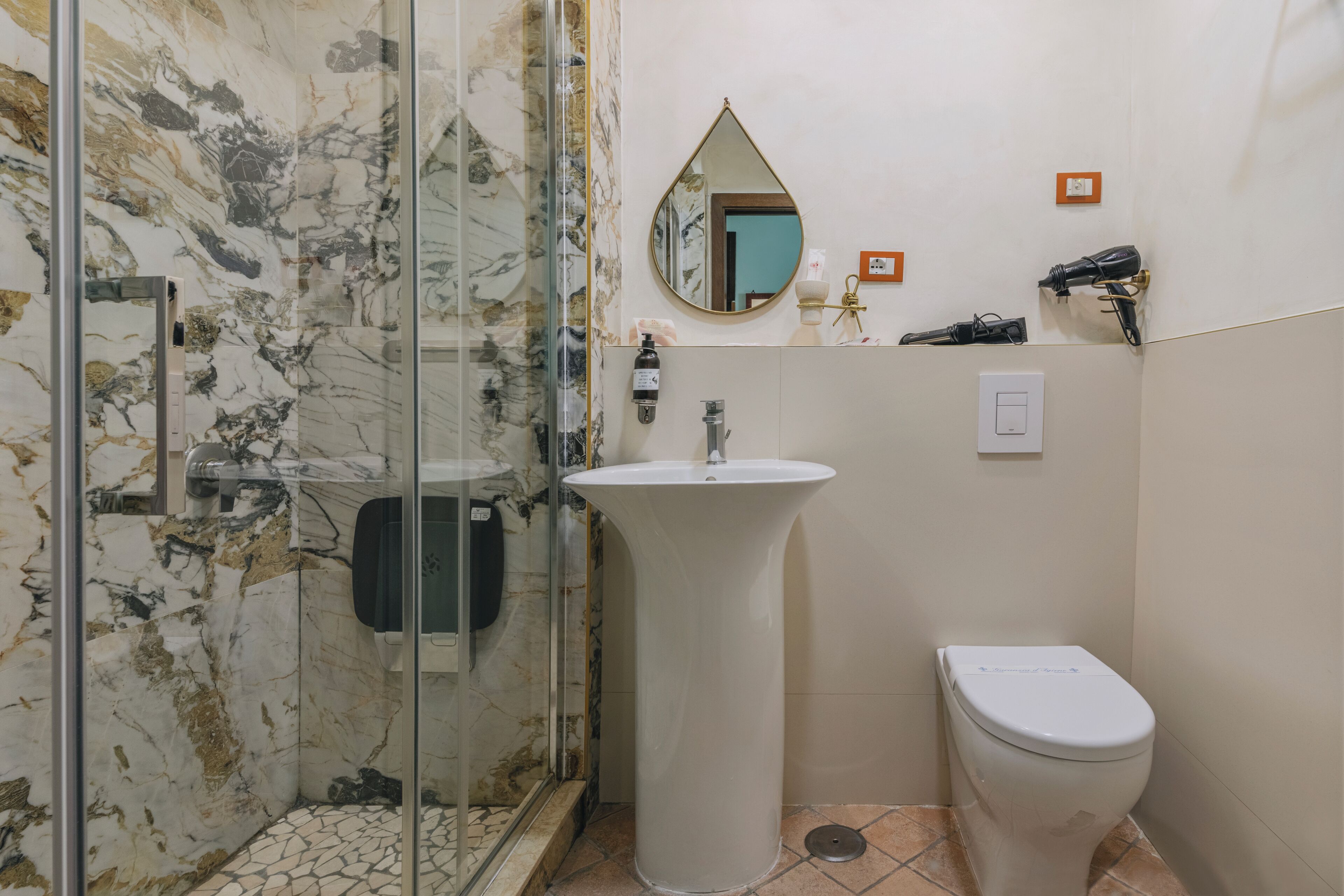 A bathroom with a glass shower enclosure, a pedestal sink, and a toilet.
