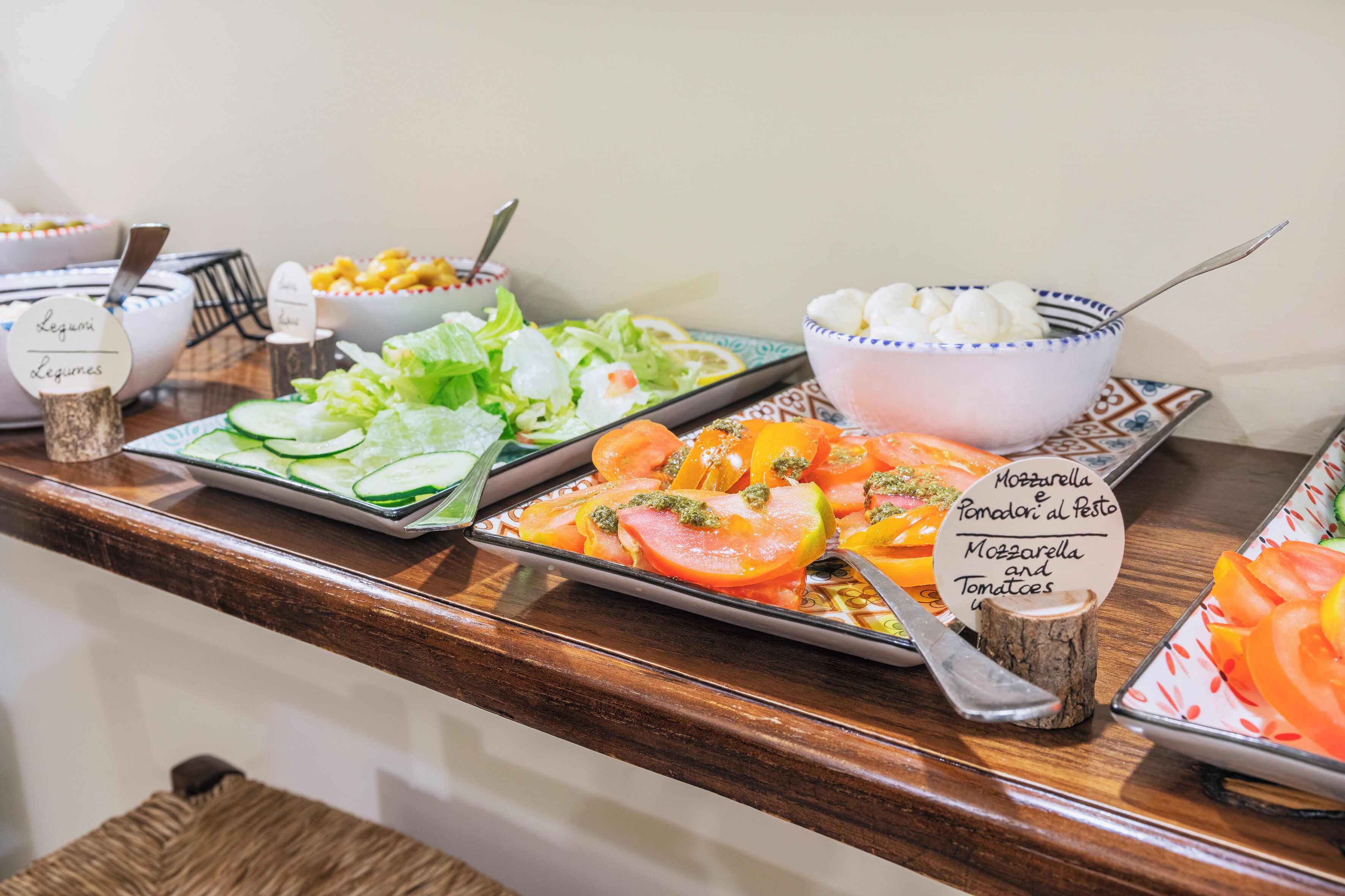 A buffet with various dishes including salads, vegetables, and a bowl of mozzarella and tomatoes.