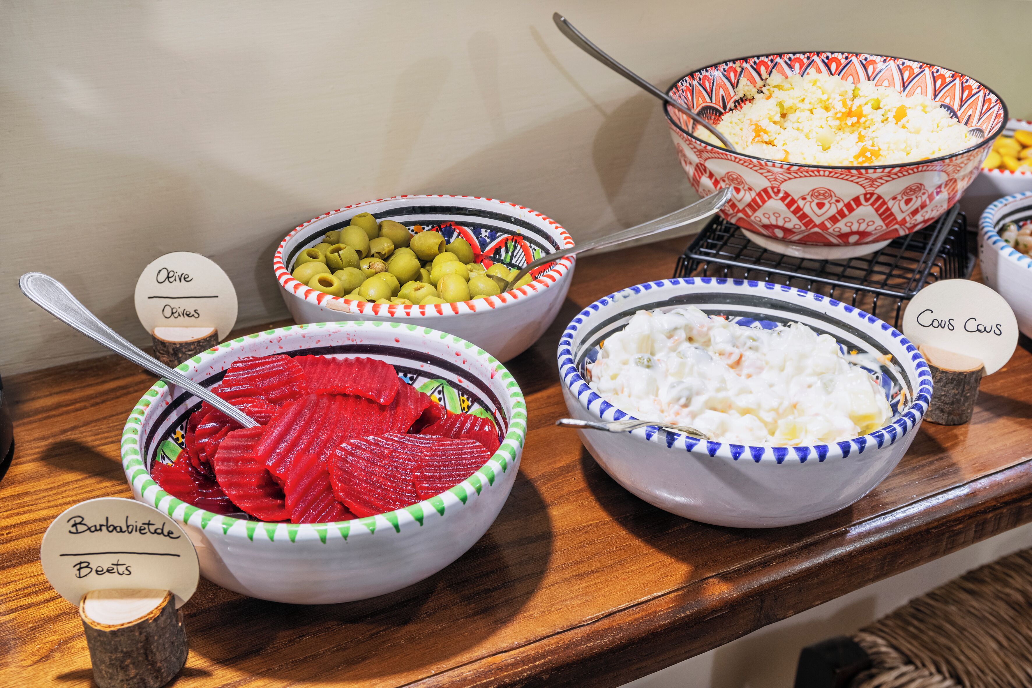 A buffet table with various food items labeled in different languages.