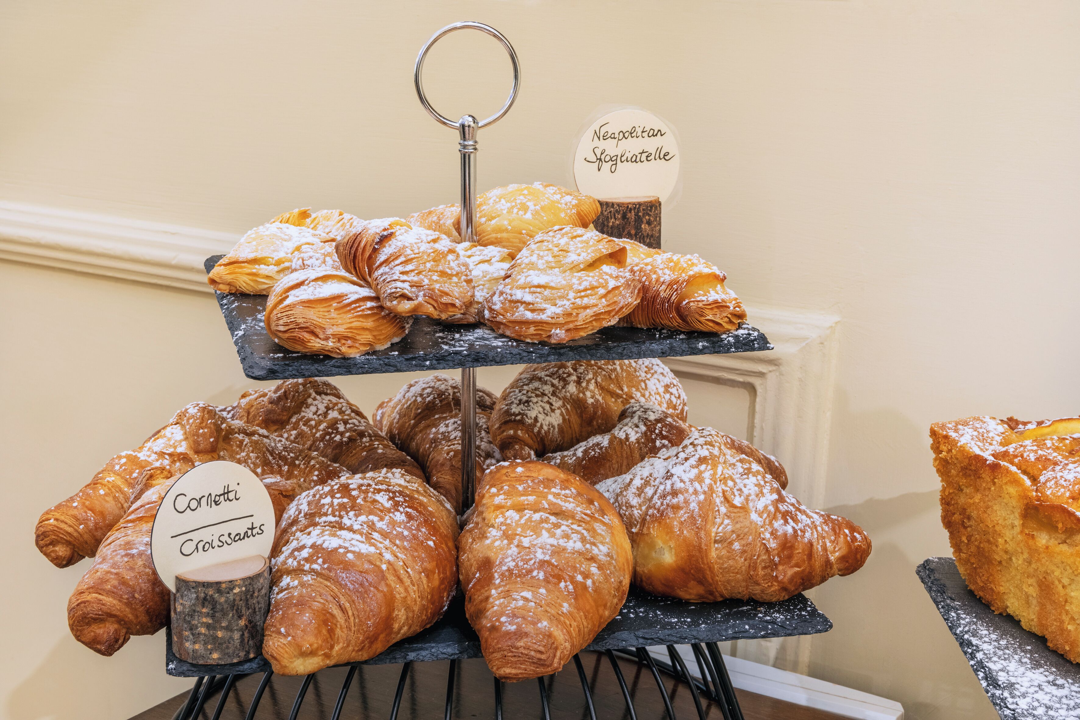 Presentació de pastissos variats en un aparador de diversos nivells, incloent croissants i altres productes de forneria.