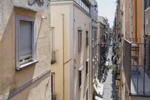 Una stretta via fiancheggiata da edifici a più piani, balconi e zone con tavoli all'aperto.