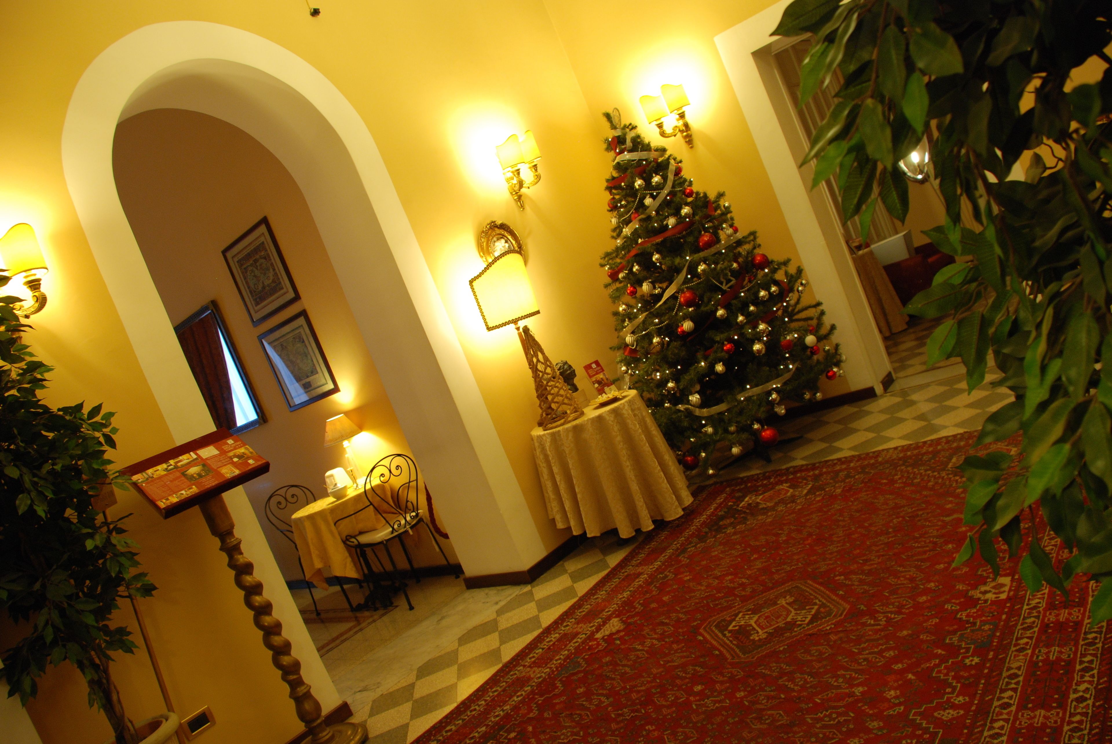 A warmly lit room with a Christmas tree, a checkered floor, and a red carpet.