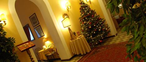 A warmly lit room with a Christmas tree, a checkered floor, and a red carpet.