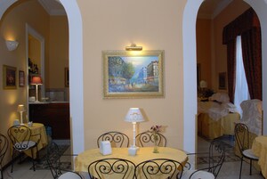 Una camera d'albergo con zona pranzo, un quadro al muro, una lampada e un letto a baldacchino.