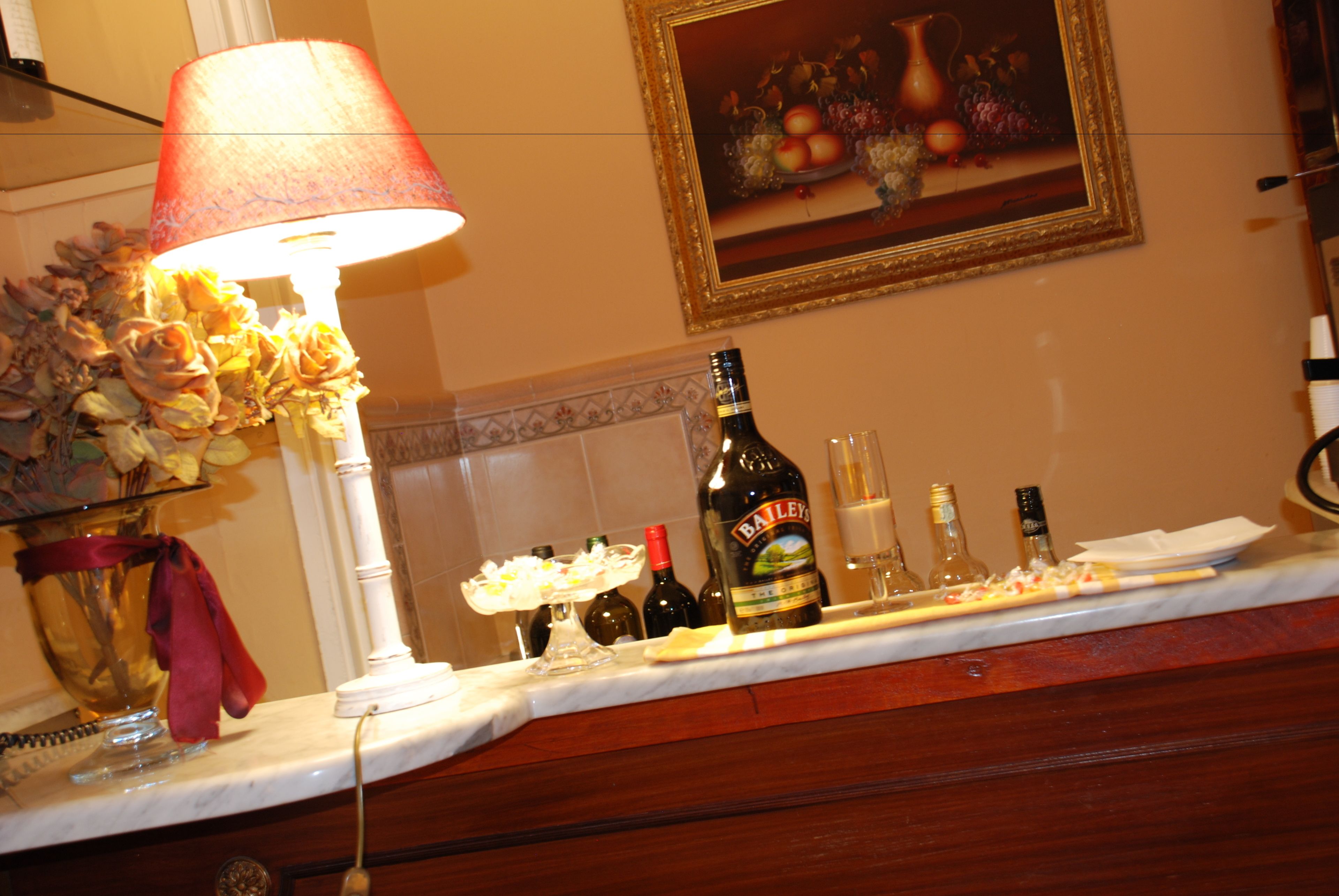 A kitchen counter with a bottle of Bailey's whiskey, a wine glass, and a vase of flowers.