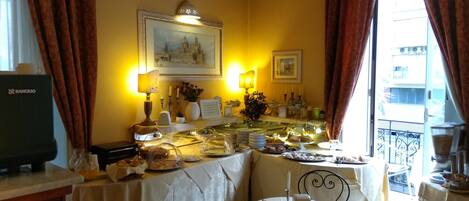 A dining area with a table set for a meal, a television, and a view of the outside balcony.