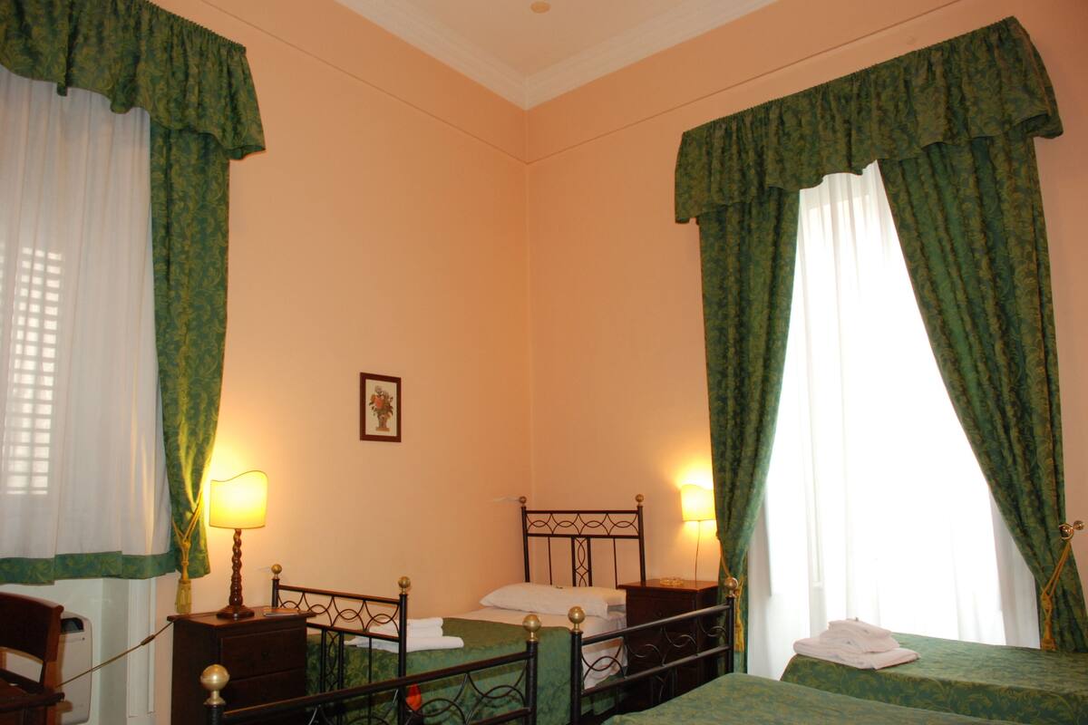 A hotel room with a bed, bedside tables, lamps, and curtains.