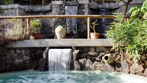 Ein Wellnessbereich mit Steinwand, Wasserfall und Whirlpool.