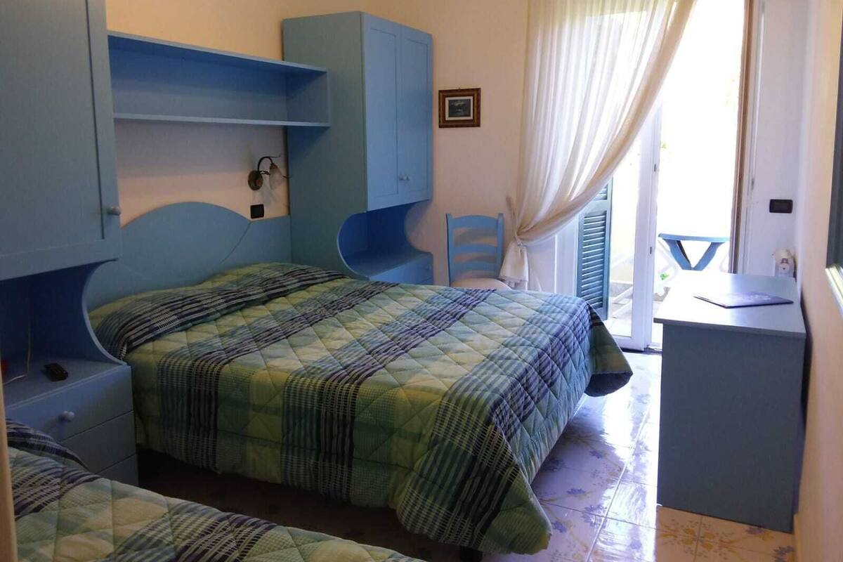 Habitación triple, vistas parciales al mar | Caja fuerte, escritorio, wifi gratis y ropa de cama