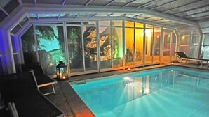 An indoor swimming pool with clear glass walls, lounge chairs, and a candle on the poolside. - Adua & Regina di Saba (Montecatini Terme)