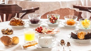 A breakfast setting with croissants, fruit salad, and a cup of coffee on a table. - Hotel L' Antico Pozzo San Gimignano (San Gimignano)