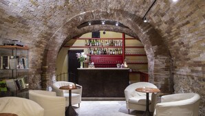 A cozy bar area with brick arches, white leather chairs, and a bar counter stocked with bottles. - Hotel L' Antico Pozzo San Gimignano (San Gimignano)