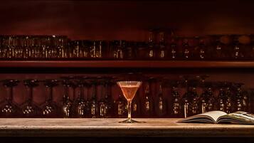 Un bar con botellas, vasos y un libro abierto sobre una barra.