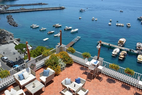 A terrace with outdoor seating overlooking a marina with several boats.