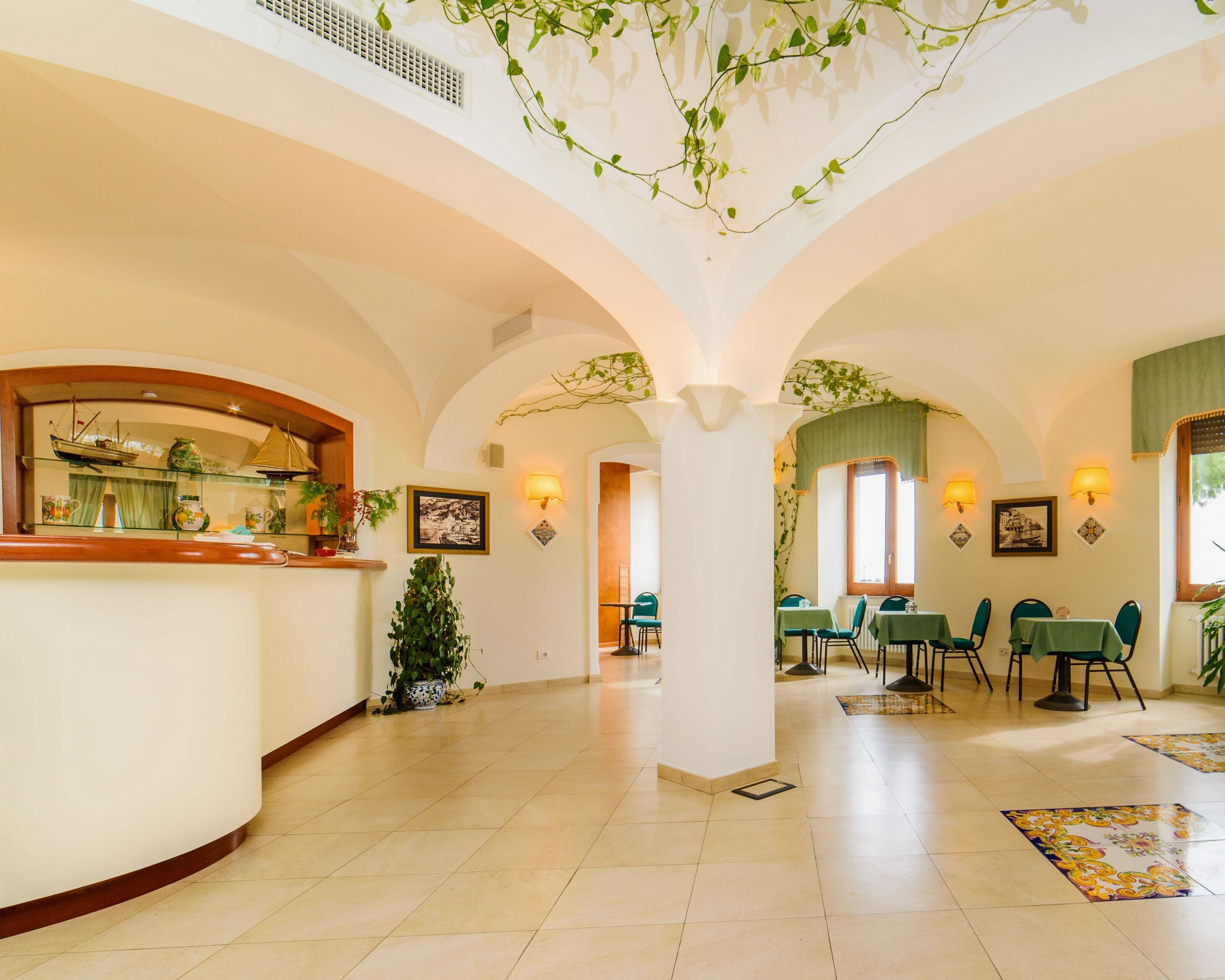 A spacious lobby with a high ceiling, arched columns, and a central seating area with tables and chairs.