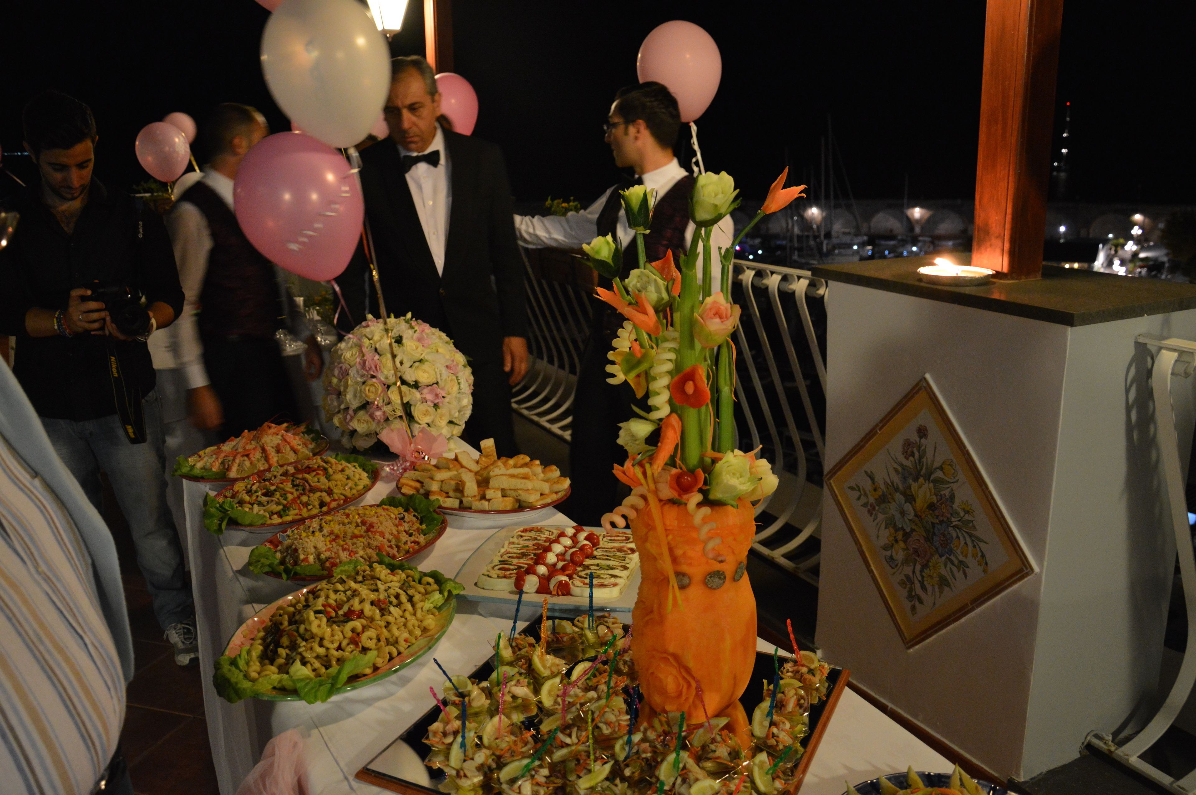 Una mesa de buffet con diferentes platos, un centro de mesa floral y globos.