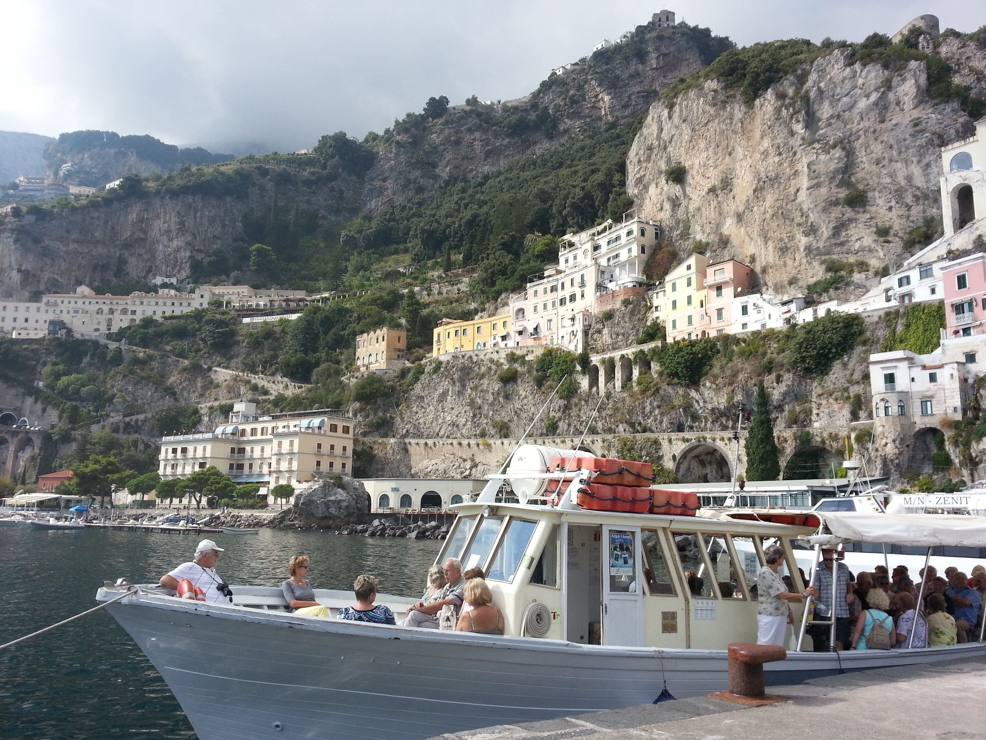 A boat docked at a harbor with a mountainous backdrop.
