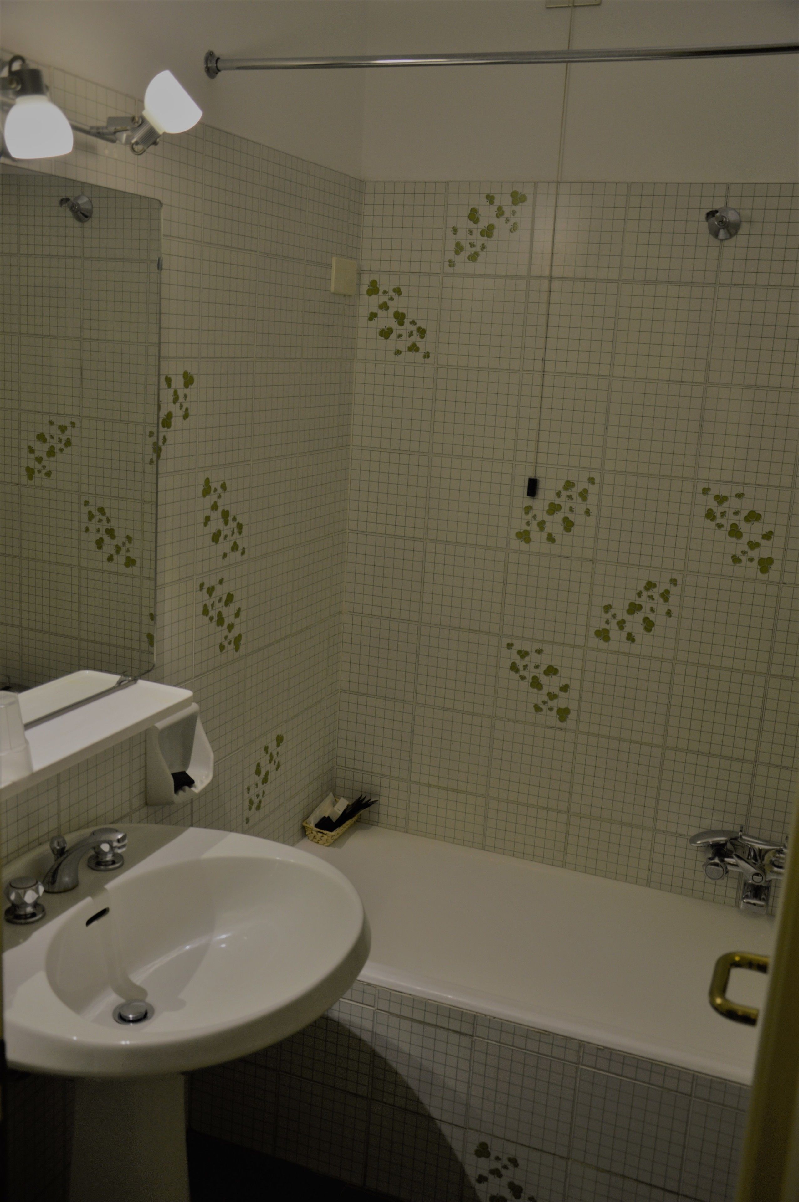 A bathroom with a white sink, a bathtub, and a mirror.