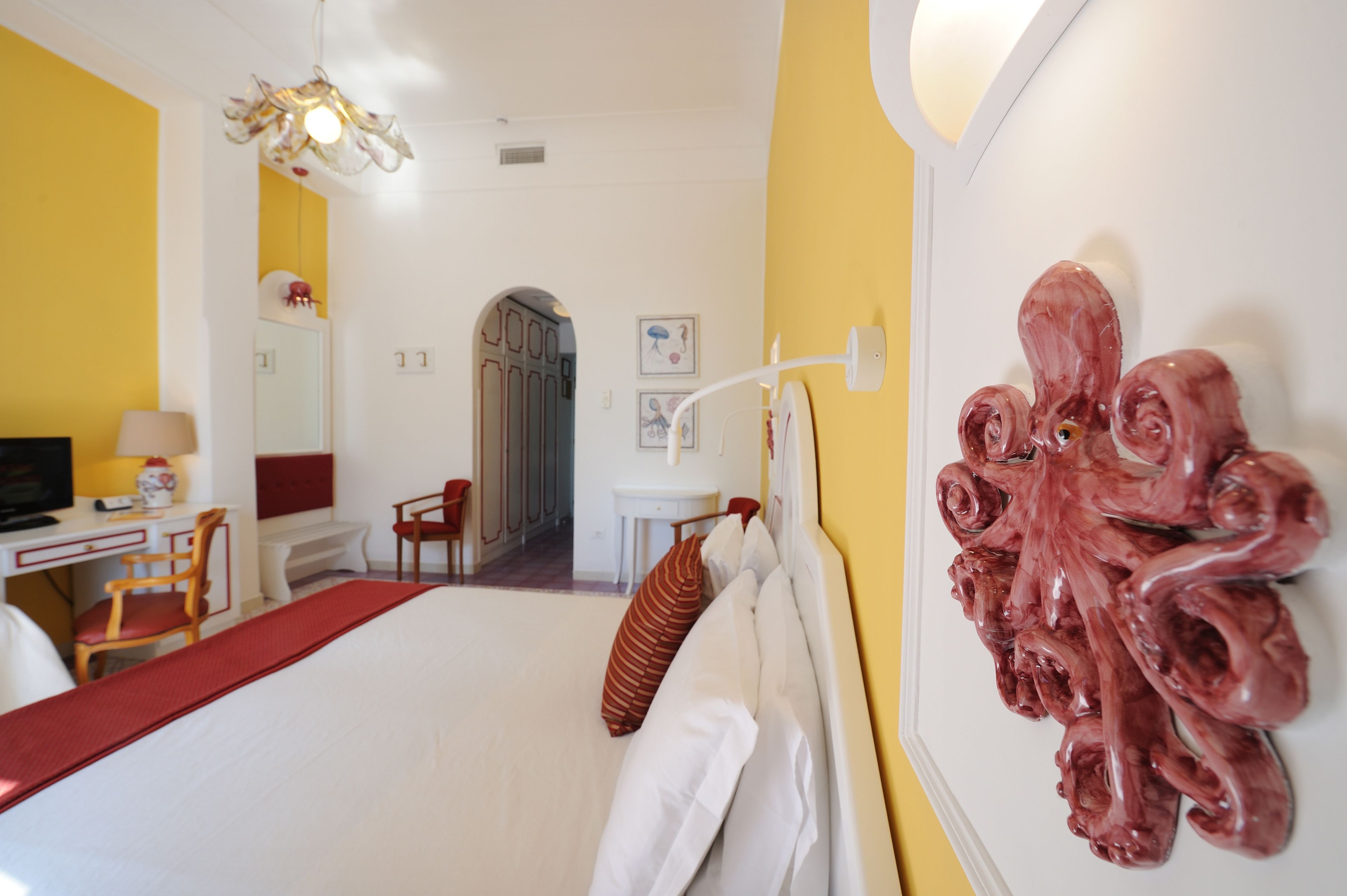 A hotel room with a bed, a desk, a chair, a television, and a unique wall decoration.