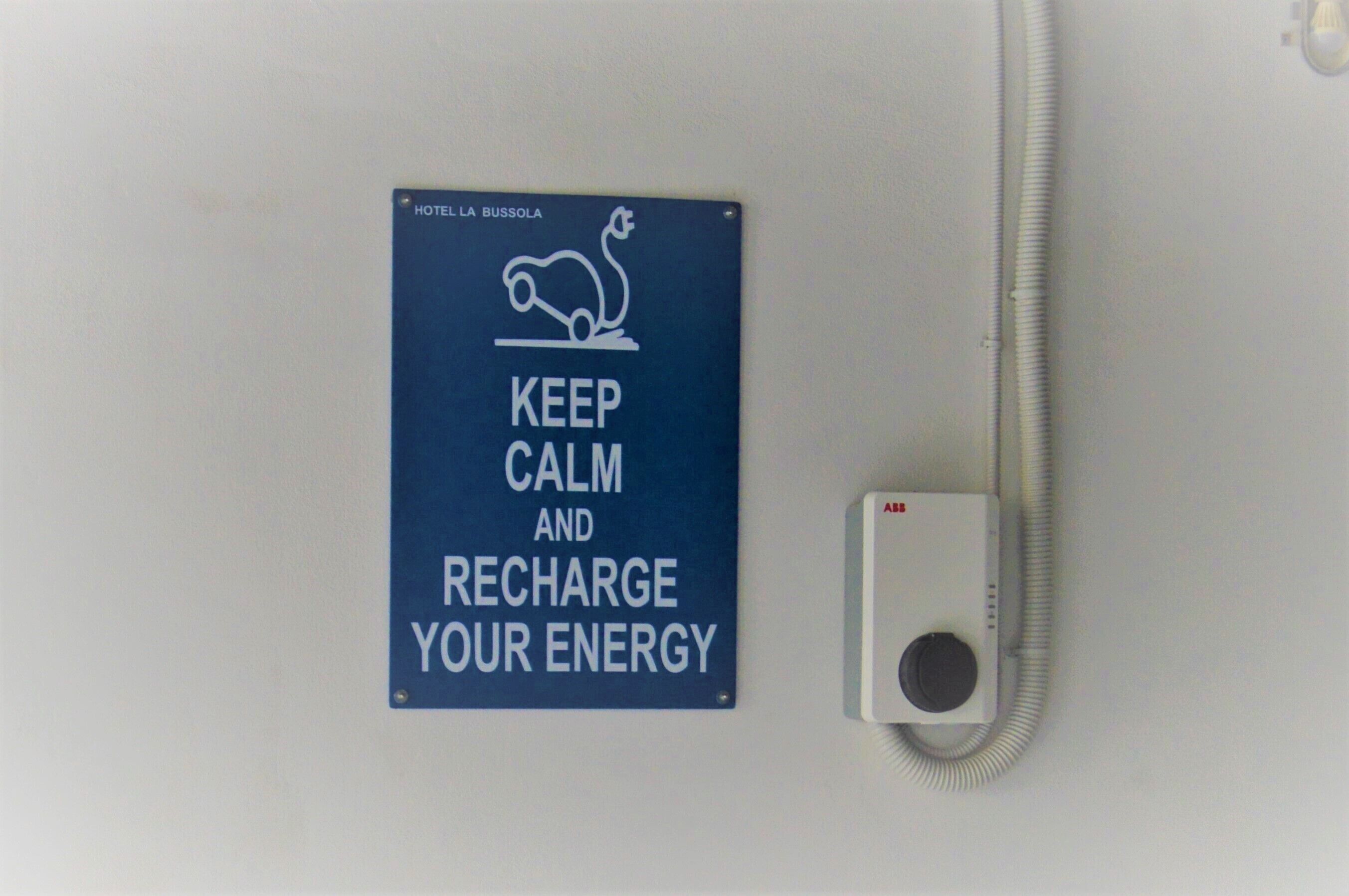 A sign with a cartoon snake and text advising to keep calm and recharge energy, next to a wall-mounted device.