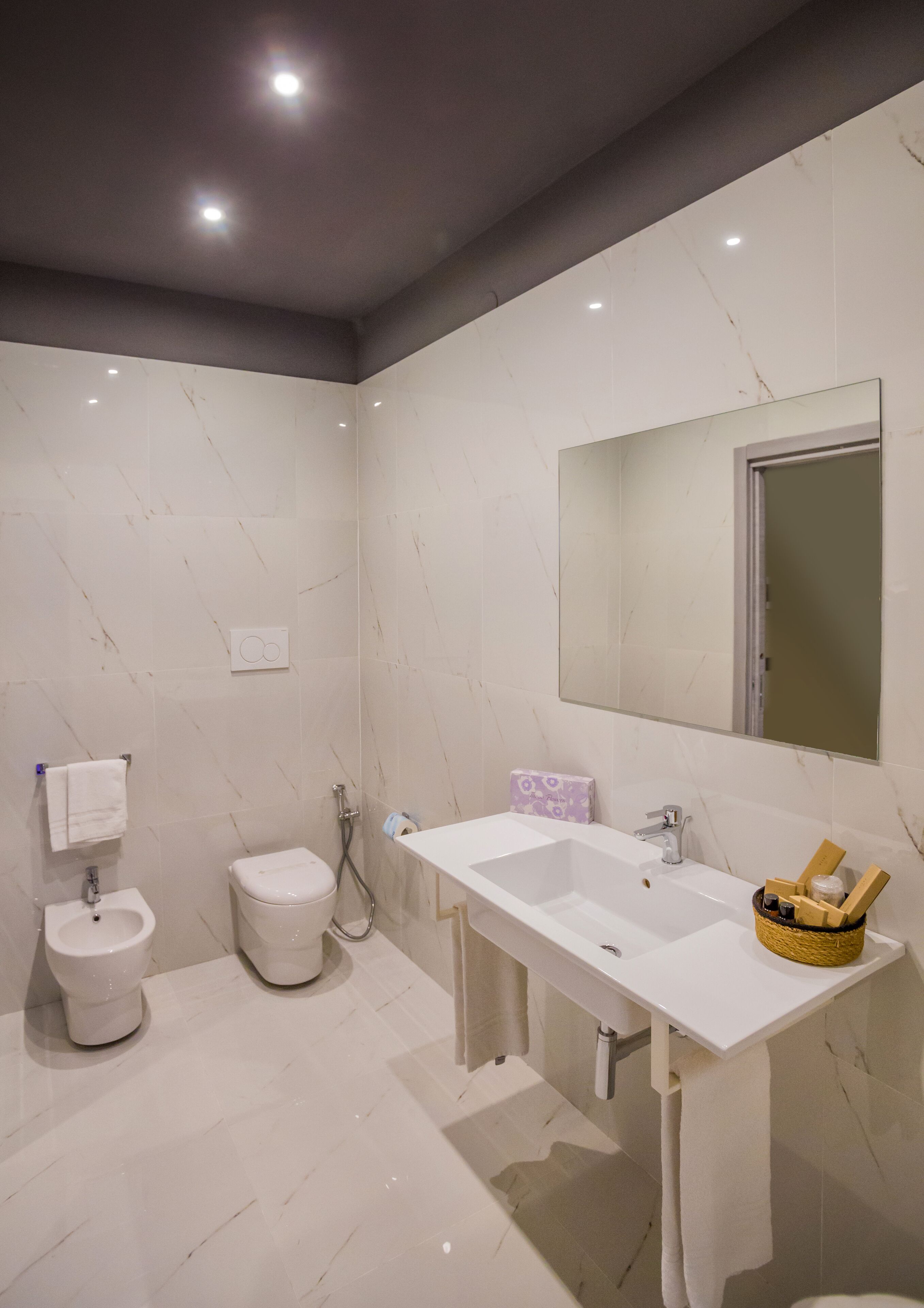 Un baño moderno con lavamanos, espejo y retrete blancos.