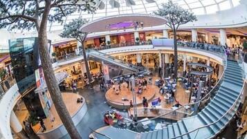 A multi-level shopping mall with a central atrium, escalators, and seating areas.