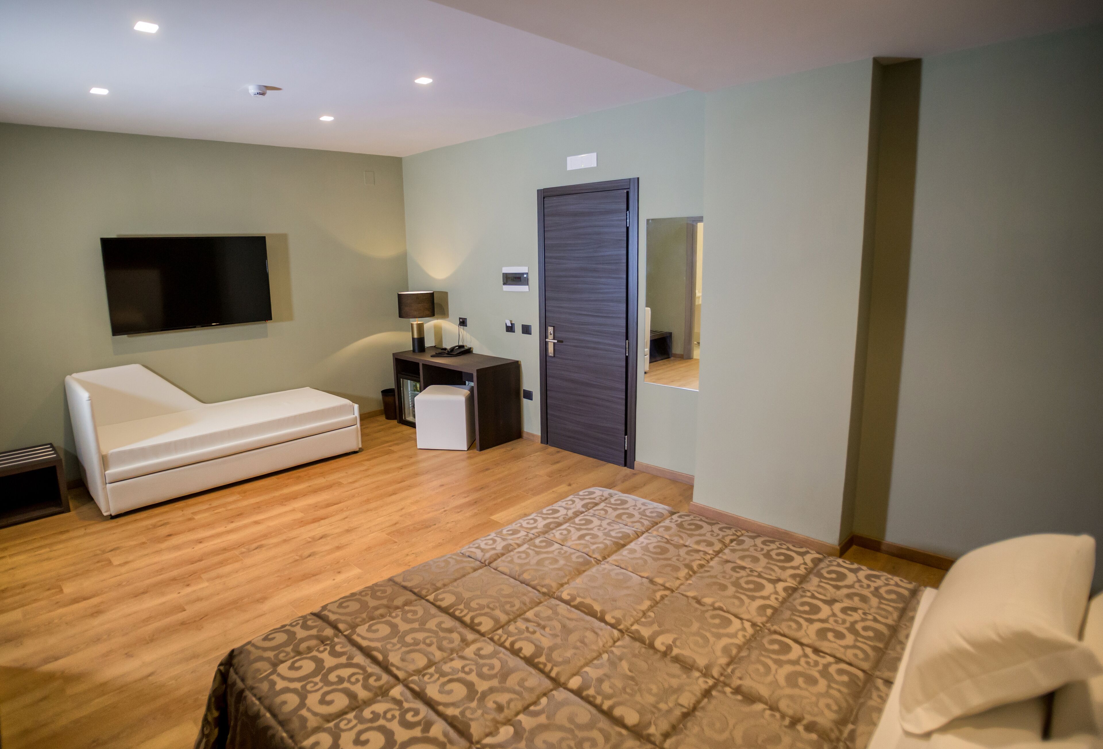 Une chambre à coucher moderne comprenant un lit, un canapé, une télévision, un bureau et une armoire.