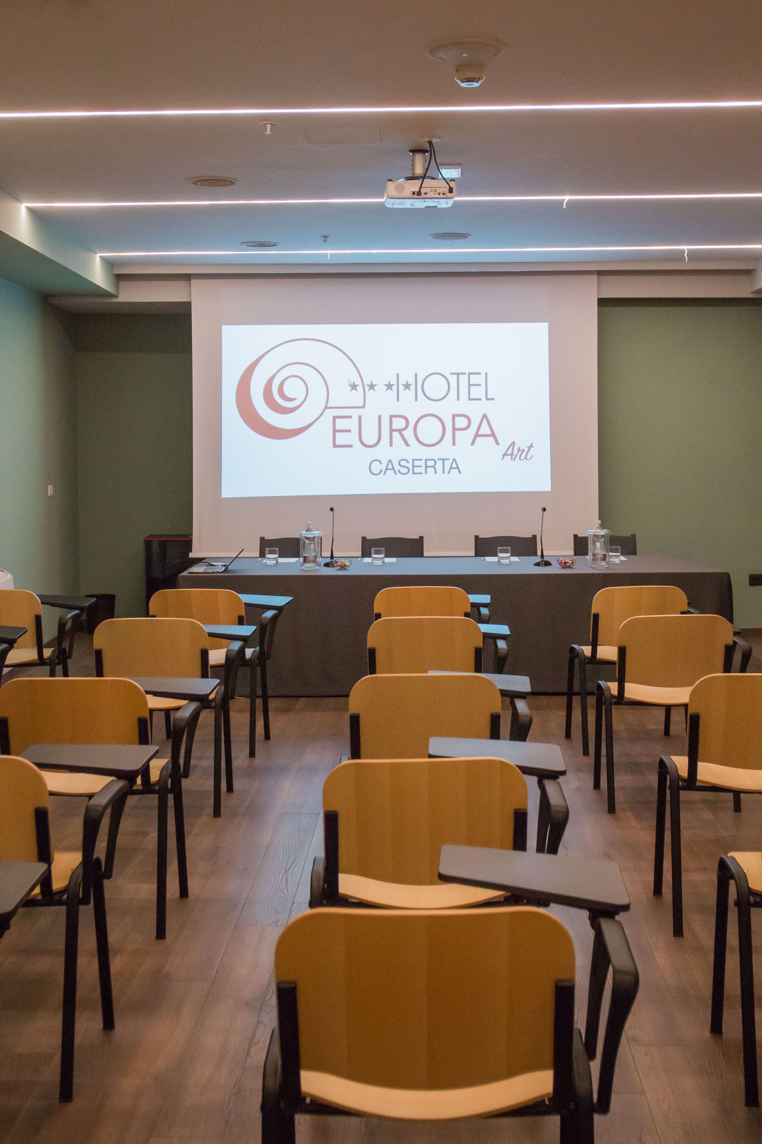 A conference room with a projection screen displaying the logo of HOTEL EUROPA CASERTA.
