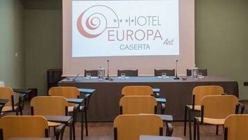 A conference room with a projection screen displaying the logo of HOTEL EUROPA CASERTA.