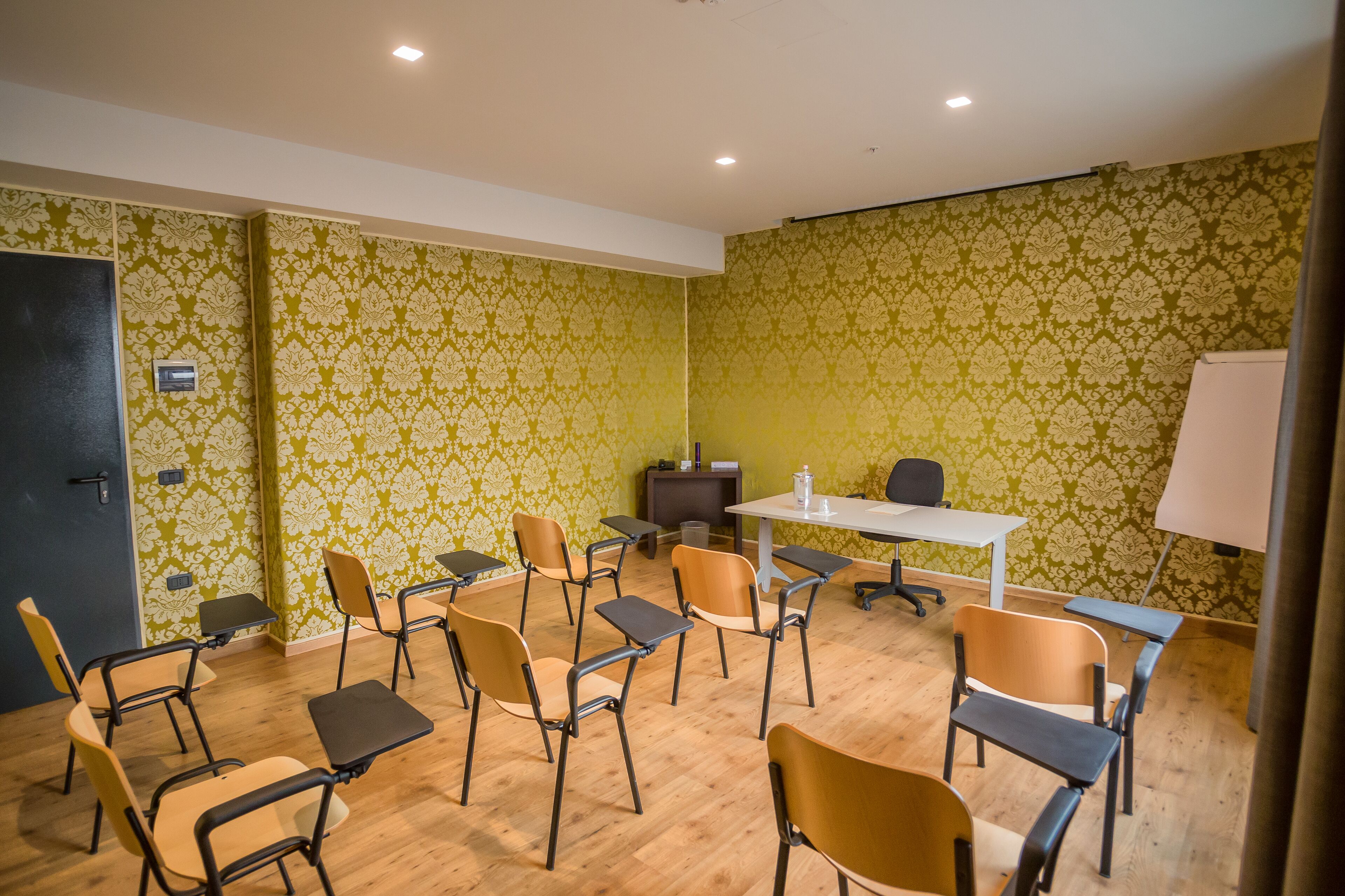 Un salón de conferencias con una mesa blanca, sillas y una pantalla para proyector.