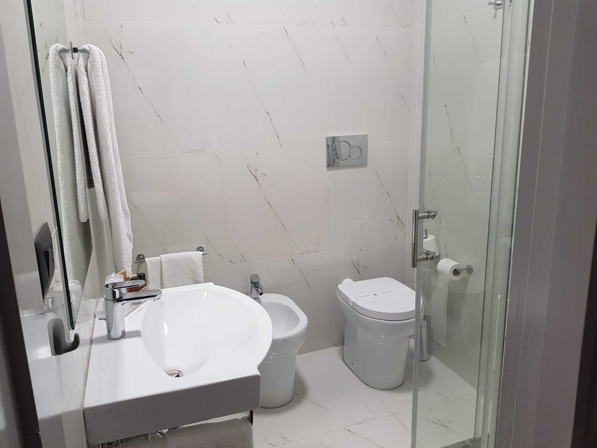 A modern bathroom with a white sink, a bidet, and a toilet.