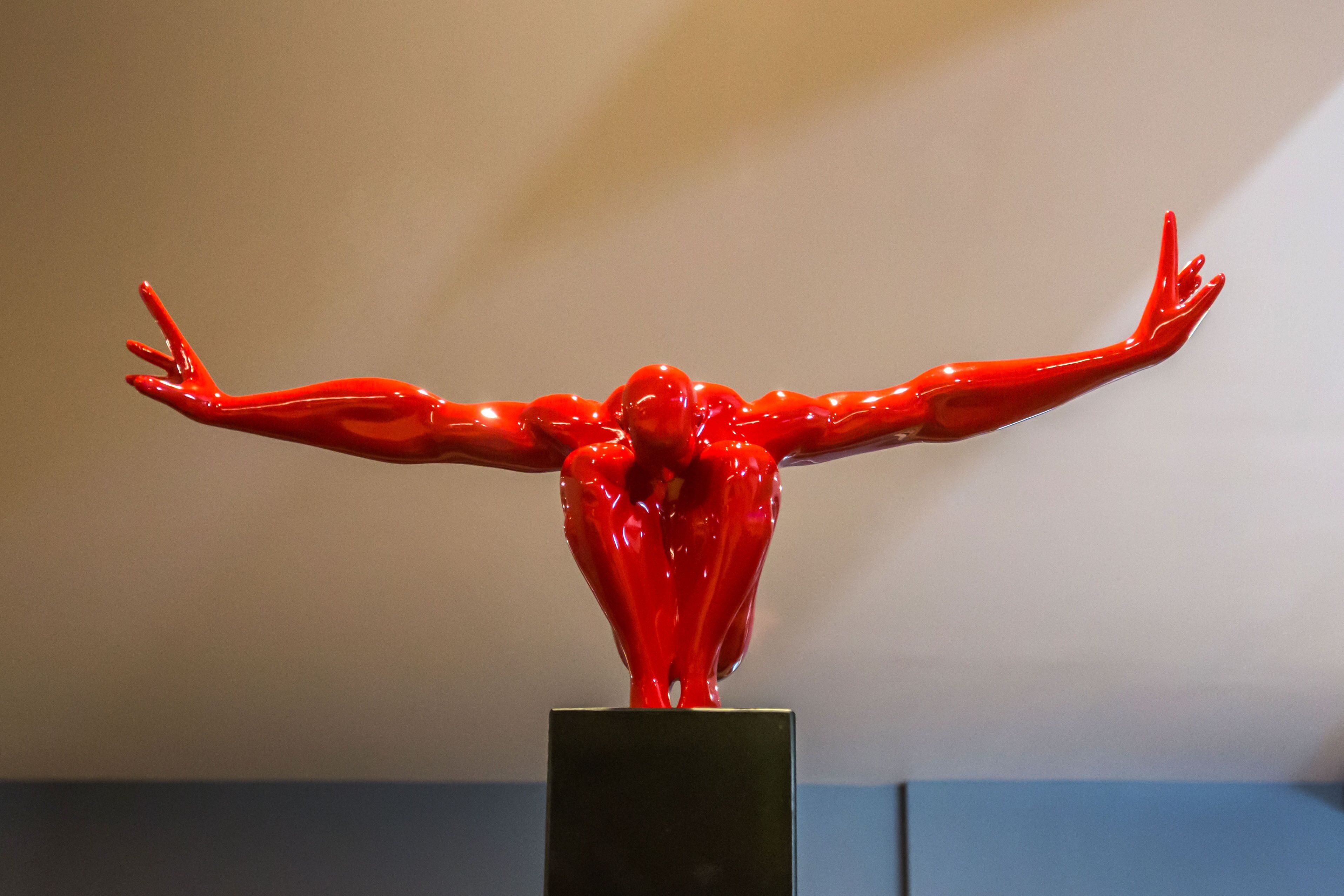 A red sculpture on a black pedestal.