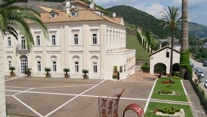A large, white building with a symmetrical facade, a central courtyard, and a small annex with an arched entrance.