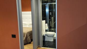 Un bagno moderno con box doccia in vetro, un WC bianco e soffione a vista.