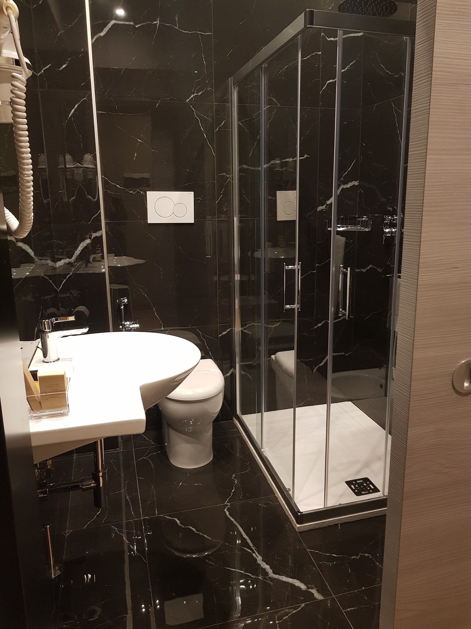 Une salle de bain moderne avec une douche à parois de verre, un lavabo blanc et des toilettes.