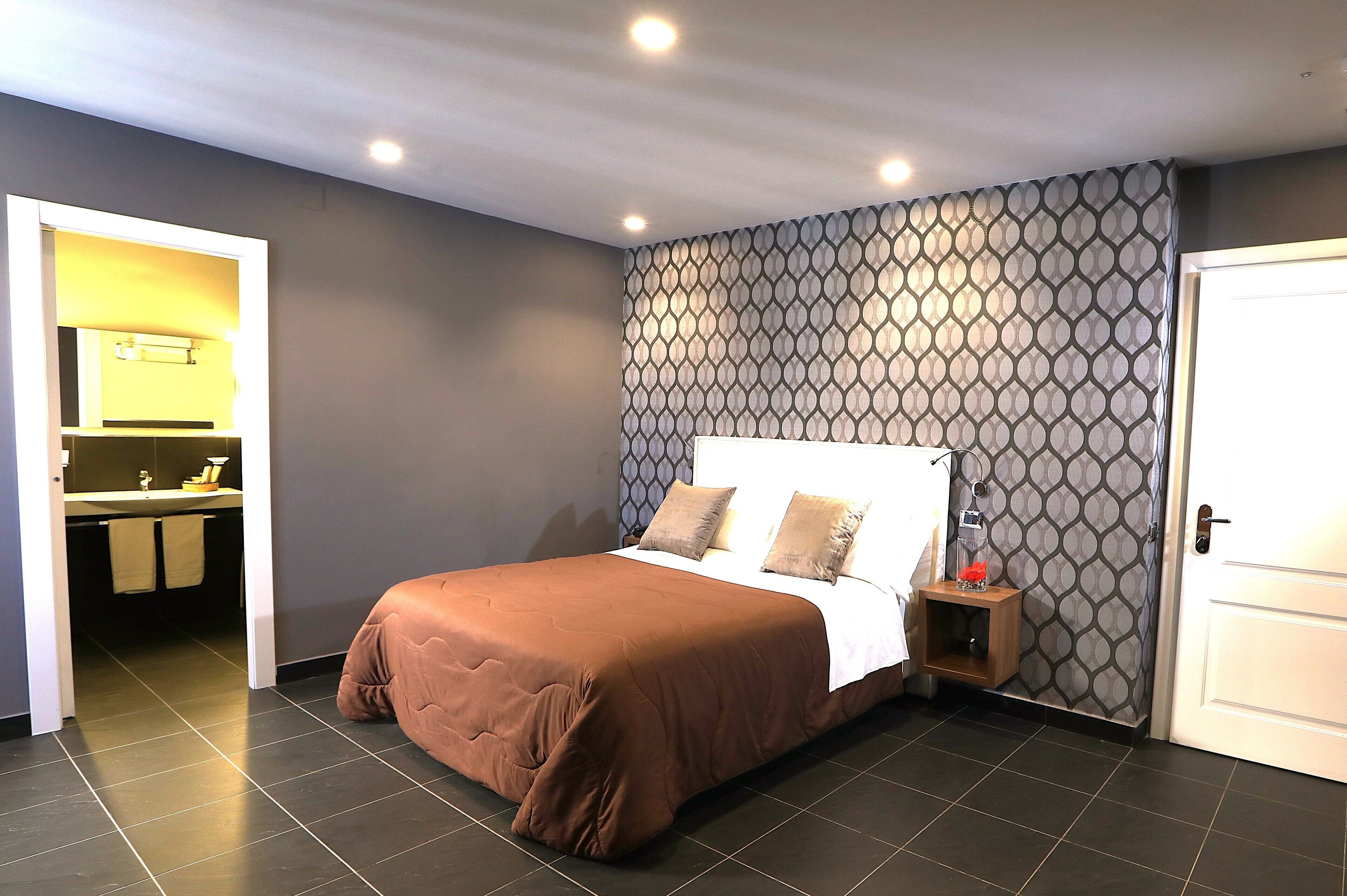 Une chambre à coucher avec un lit, une table de chevet, un miroir et une porte.