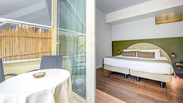 Un dormitorio con cama, mesita de noche y vistas a una valla de bambú a través de una puerta de cristal.