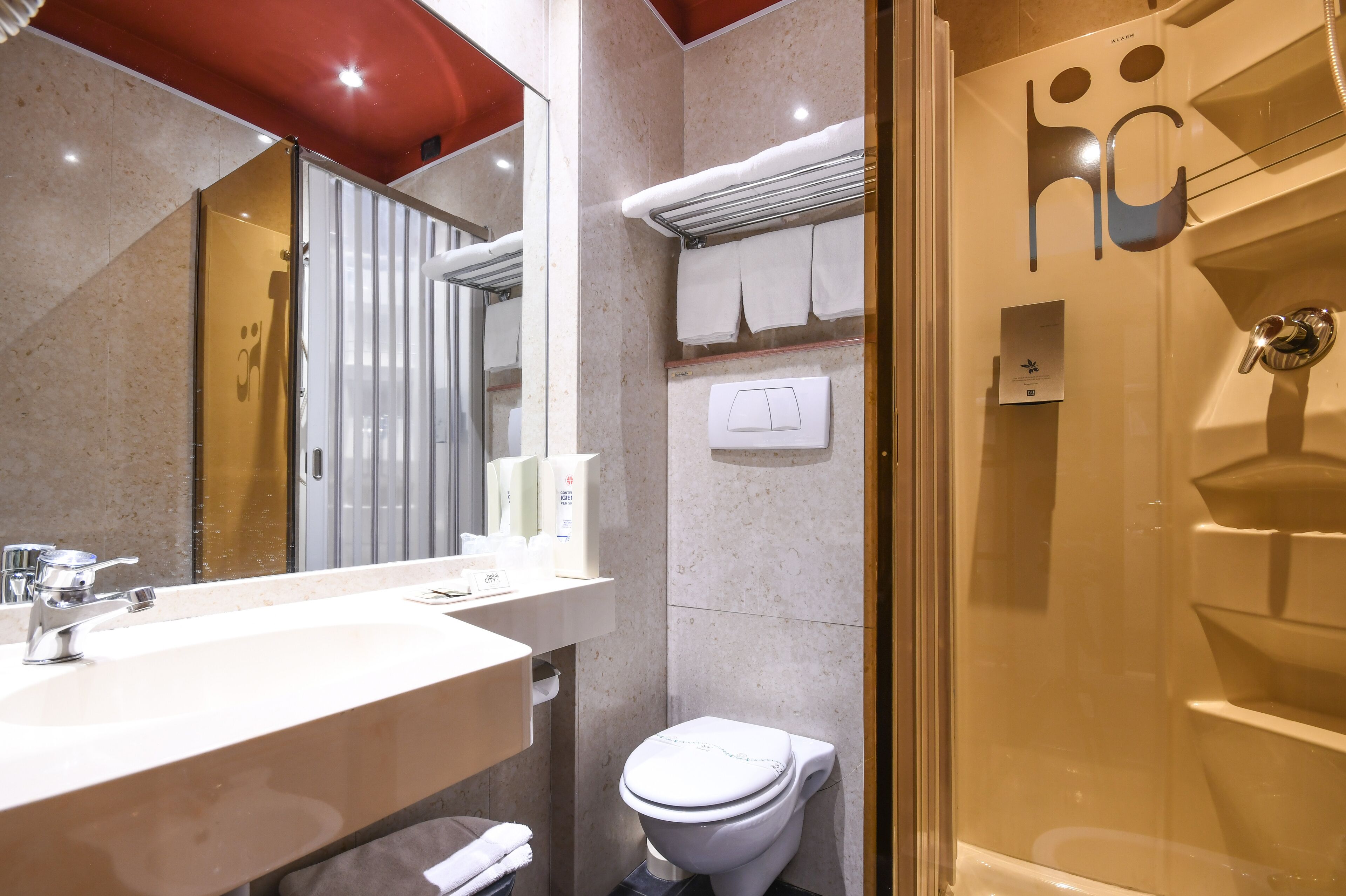 A modern bathroom with a large mirror, a sink, a toilet, and a glass-enclosed shower.