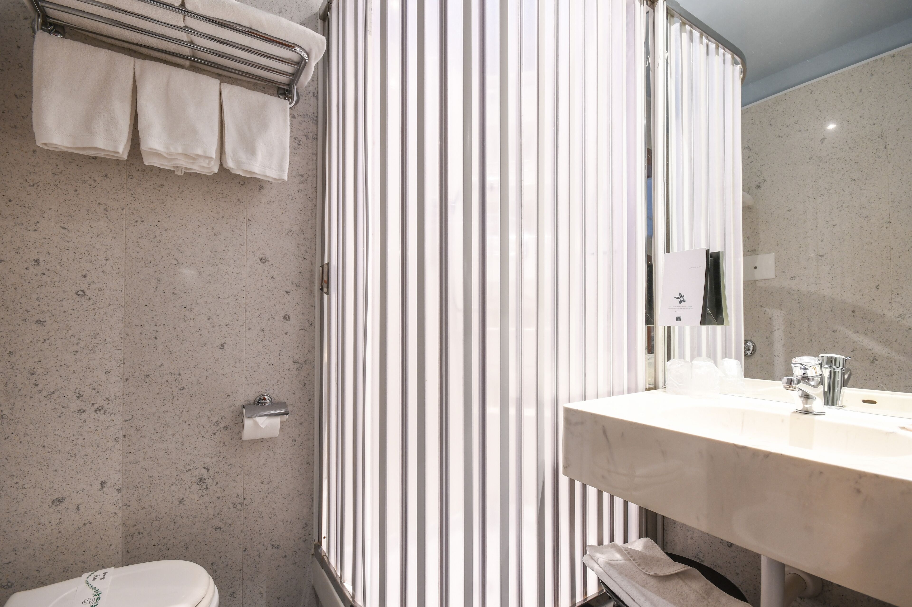 Un bagno con un lavandino in marmo, un water e una tenda da doccia a righe.