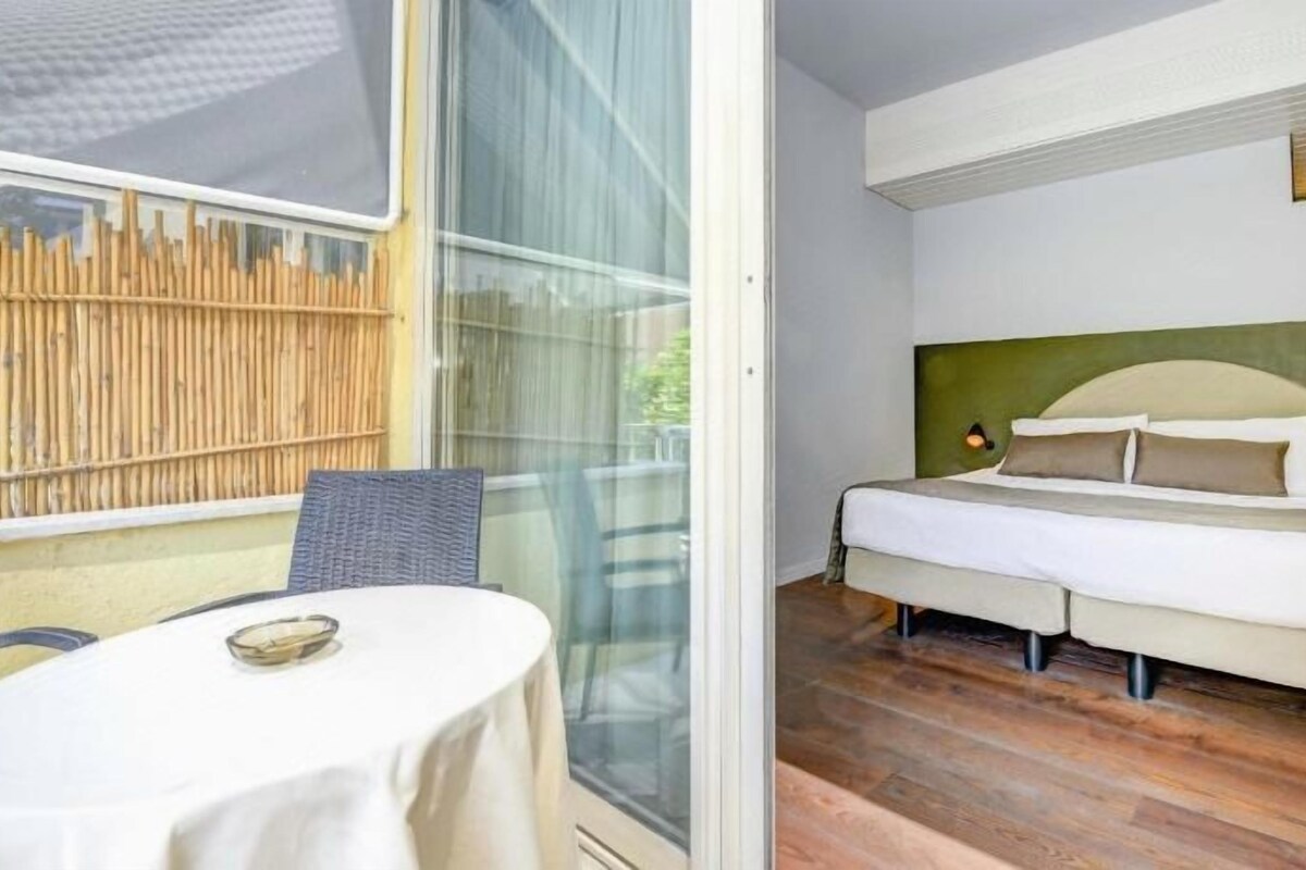 Une chambre avec un lit, une table de chevet et une fenêtre donnant sur un jardin de bambous.